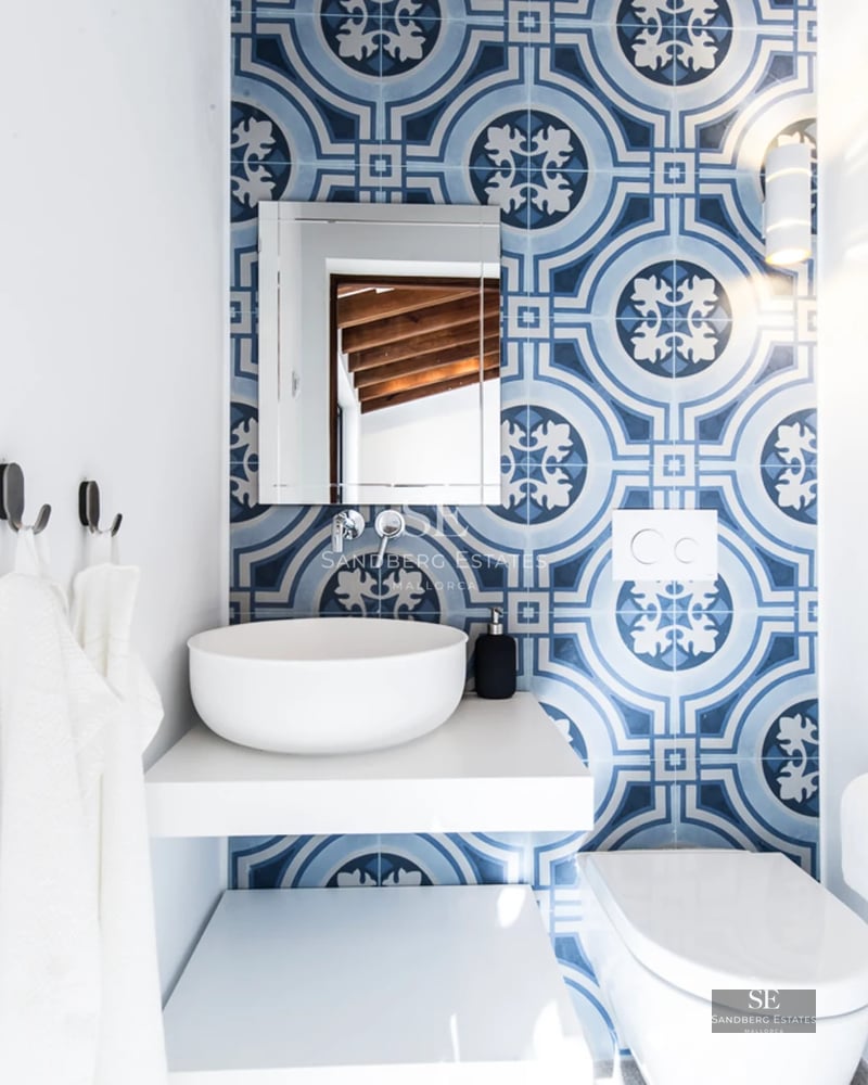 Exterior of modern villa with reflecting pool, palm trees, and minimalist architecture. Clear blue sky.