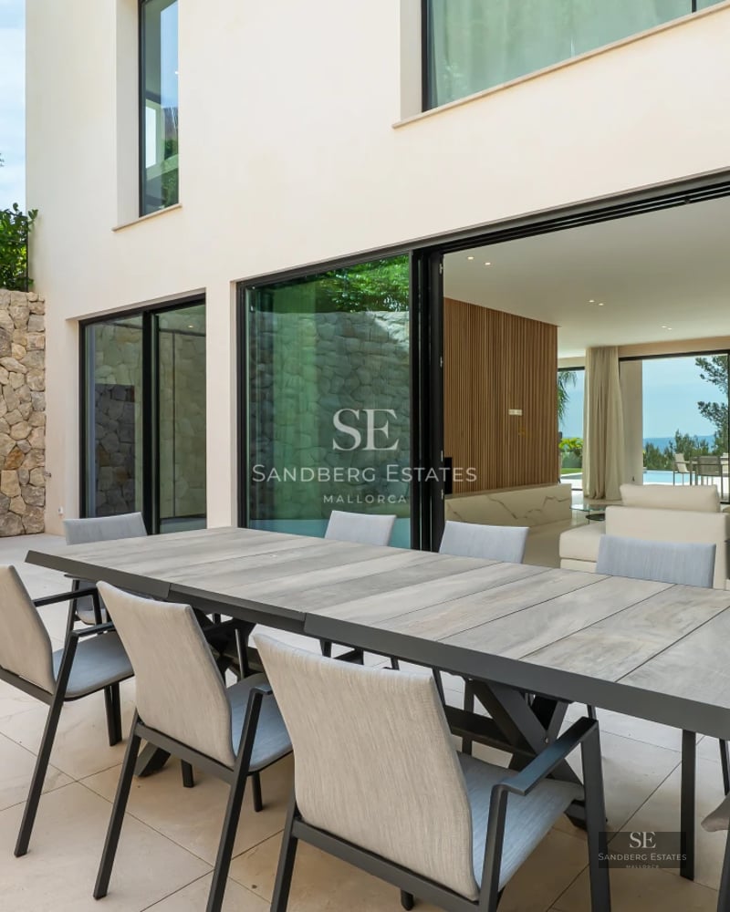 Spacious living room with panoramic sea view windows, light wood flooring, modern furniture and elegant lighting.