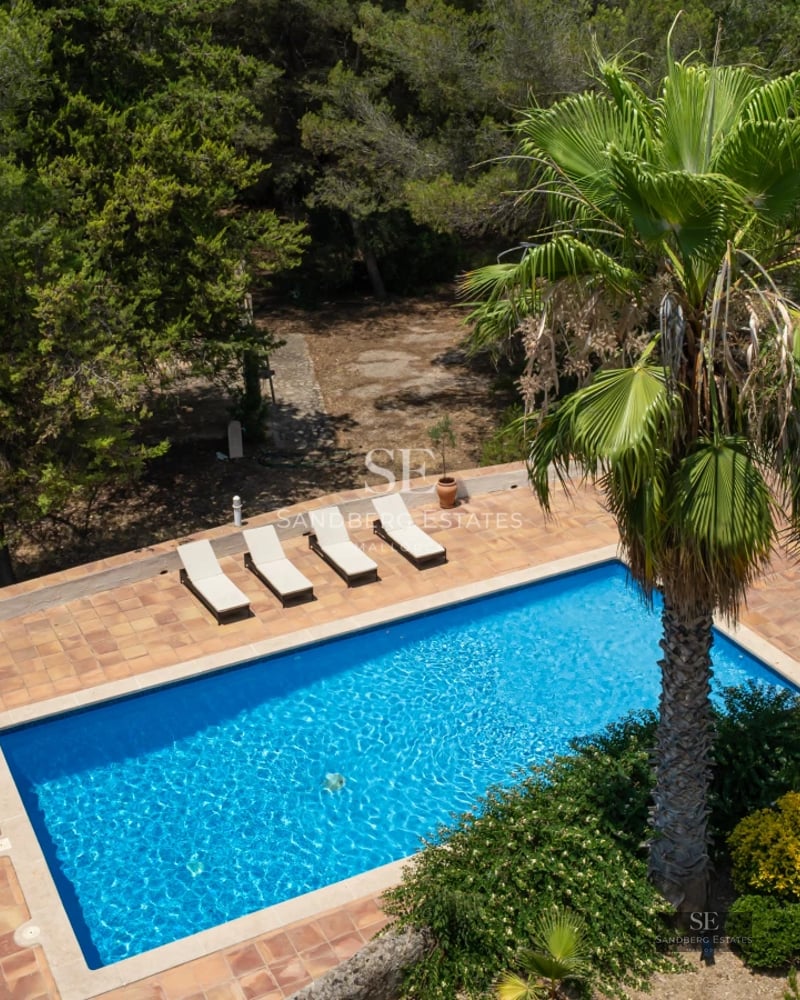 Exterior view of a modern villa featuring an infinity pool, lush gardens, and expansive terraces. Contemporary architecture and luxury finishes.
