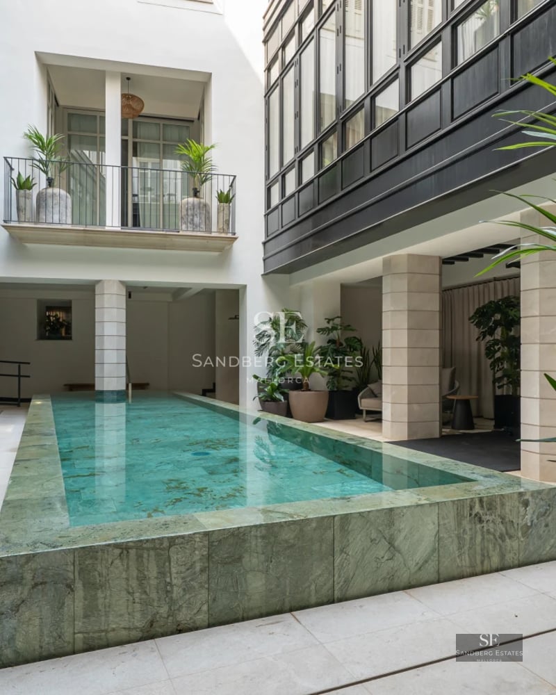 Exterior view of a modern villa featuring an infinity pool and expansive terraces overlooking the sea. Minimalist design and lush gardens.