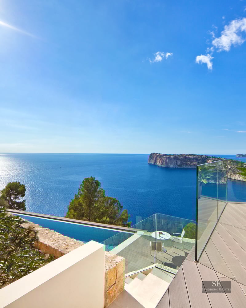 Modern terrace with glass railings overlooking the Mediterranean Sea and an infinity pool.
