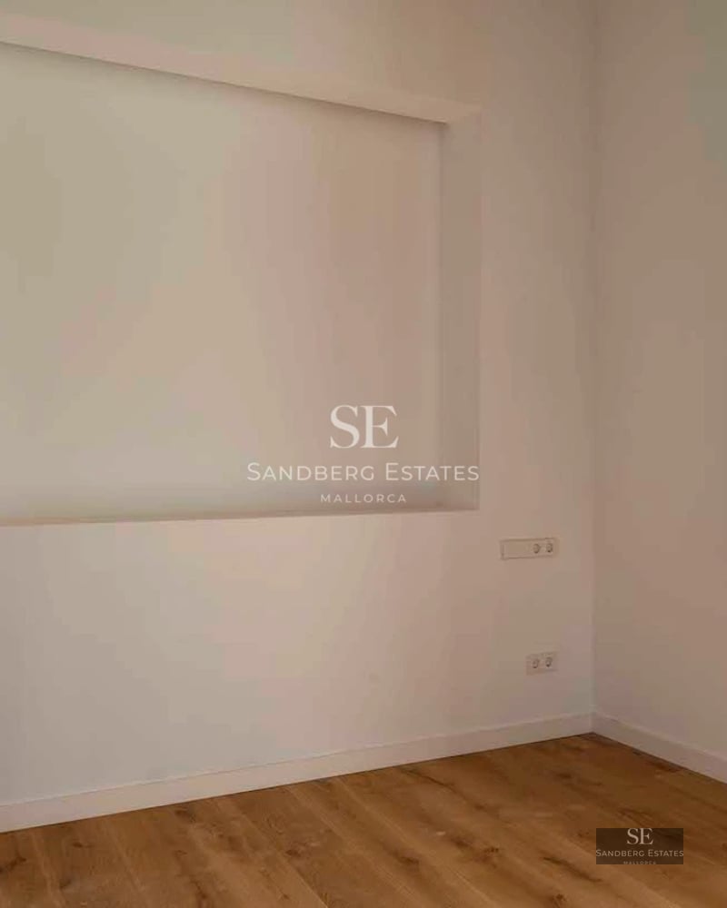 Spacious balcony with glass railings offering sea and city skyline views. Modern and elegant outdoor furniture.