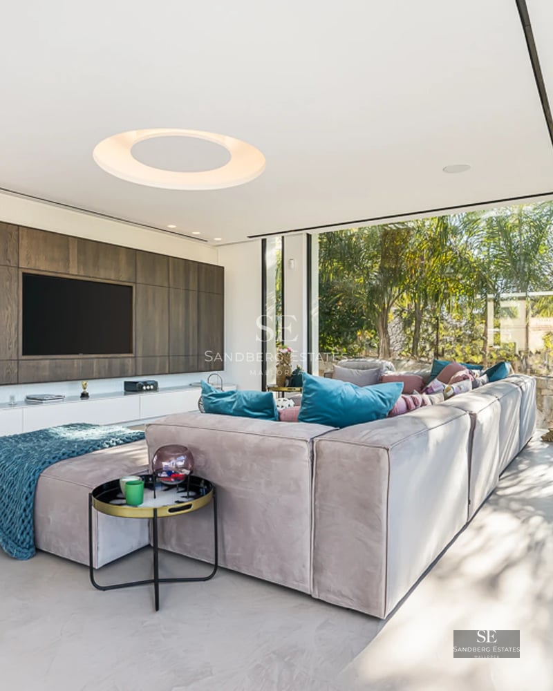 Spacious living room with picture windows, light wood floors, minimalist decor. Abundant natural lighting.