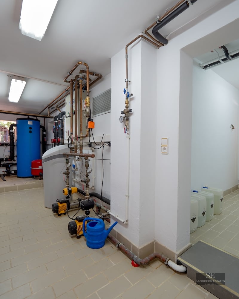 Technical room with water tanks, pumps, and copper piping on white tiled floors.