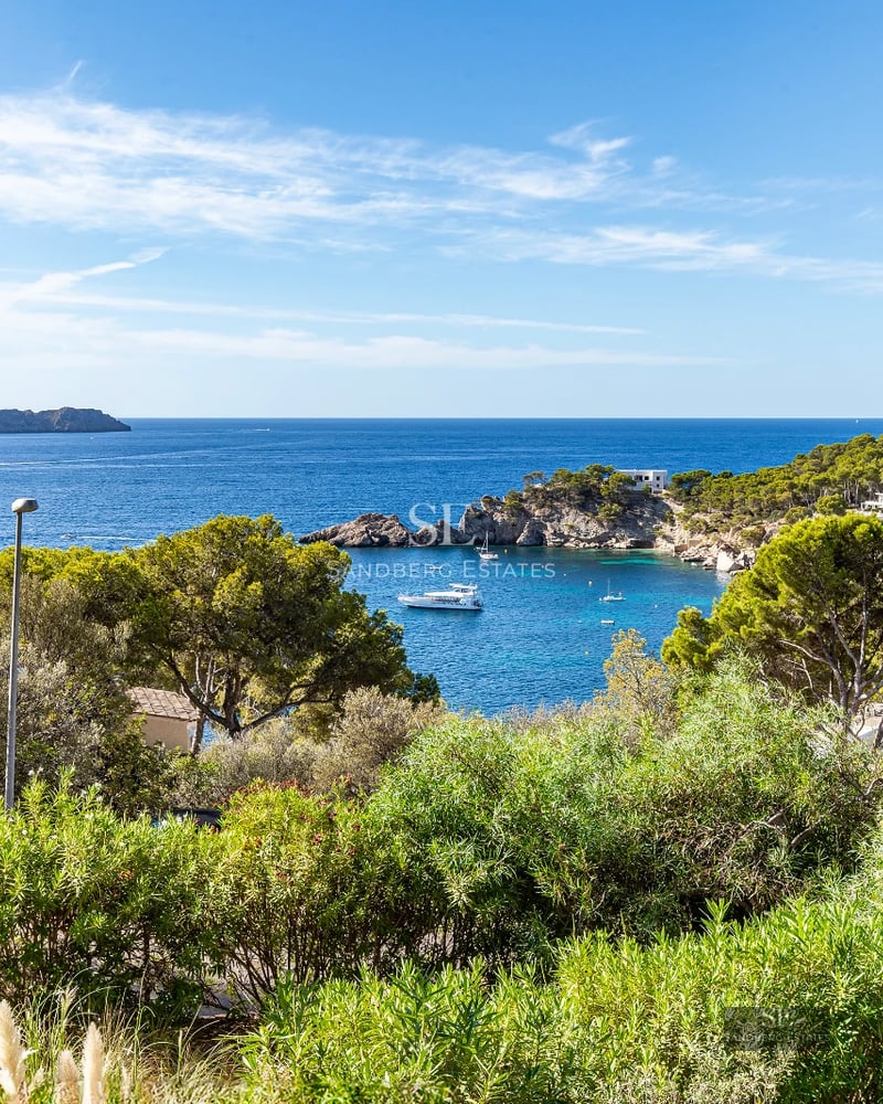 Exterior view of a modern villa with an infinity pool, surrounded by greenery. Minimalist design with large windows.
