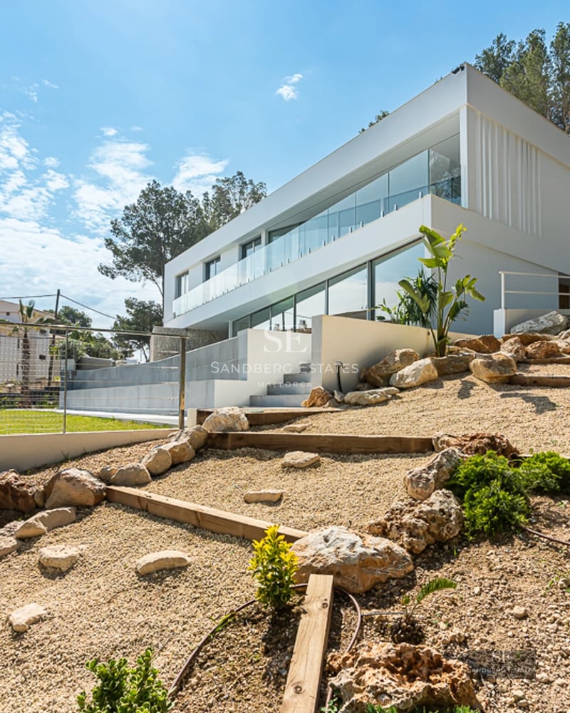Infinity pool view lined with sun loungers. Modern design with large windows and lush greenery.