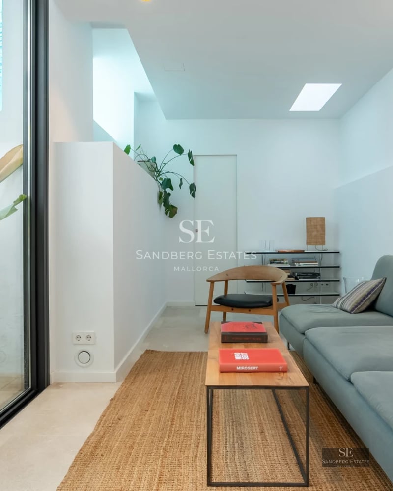 Expansive pool surrounded by lush vegetation. Elegant home with large windows and modern architecture. Clear blue sky and natural light.