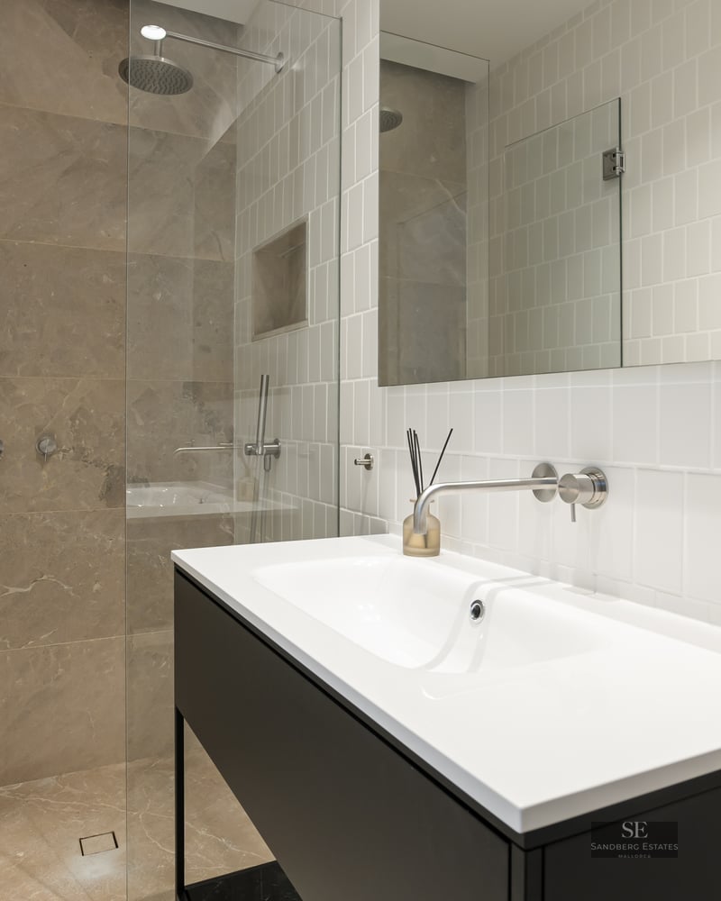 Modern bathroom with white vertical tiles, a black vanity, and a glass-enclosed stone walk-in shower.