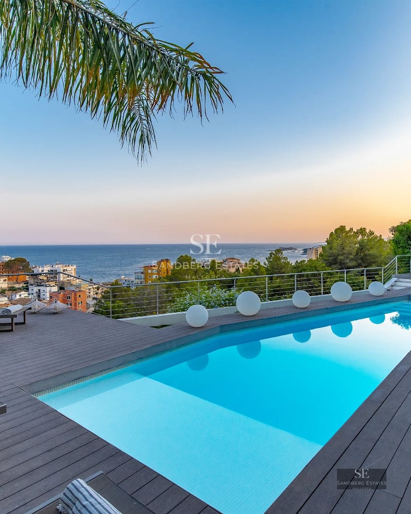 Panoramic view of a modern terrace with an infinity pool and elegant furniture. Stunning sea and horizon views.