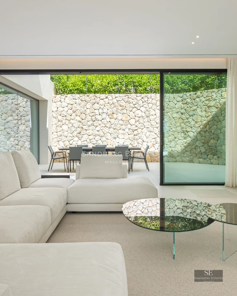 Panoramic view of a modern villa with an infinity pool. Minimalist architecture with large glass windows. Lush garden and spacious terraces.