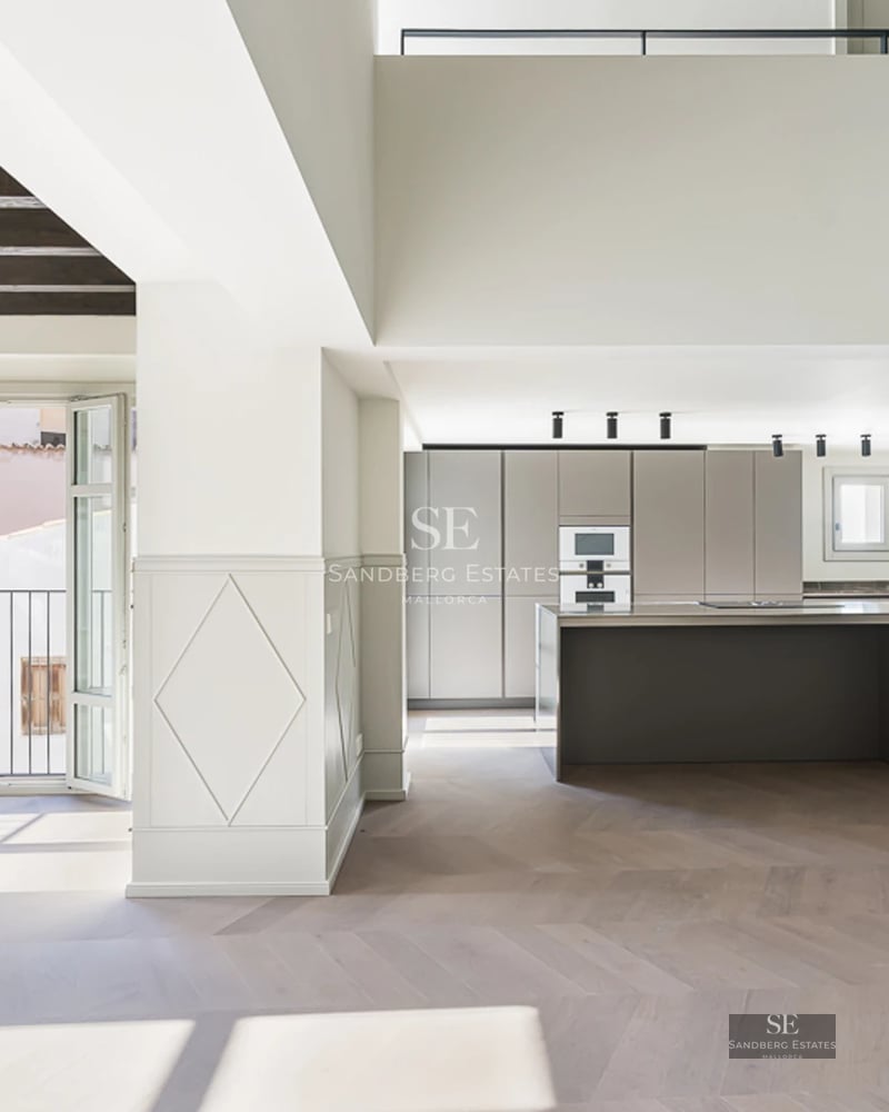 Spacious living room with picture windows, light wood floors, modern fireplace, and panoramic views. Minimalist furniture, abundant natural light.