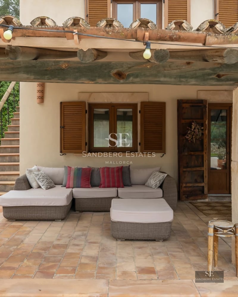 View of a bright blue swimming pool surrounded by a terrace with sun loungers and a lush garden. Modern architecture with large windows.