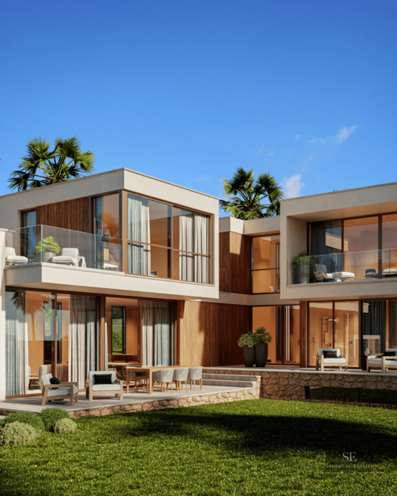 Two-story modern villa with floor-to-ceiling glass windows, wood accents, and a lush green lawn under a blue sky.