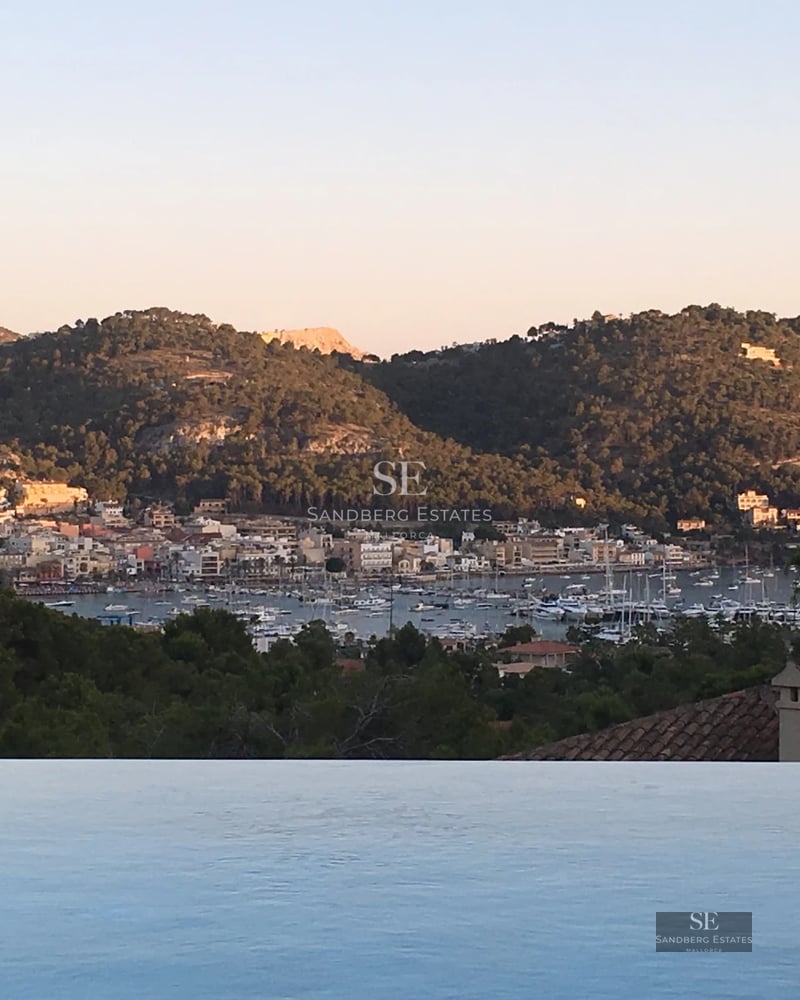 Modern terrace with sea view. Glass railing, designer outdoor furniture, and wooden flooring. Soft ambient lighting.