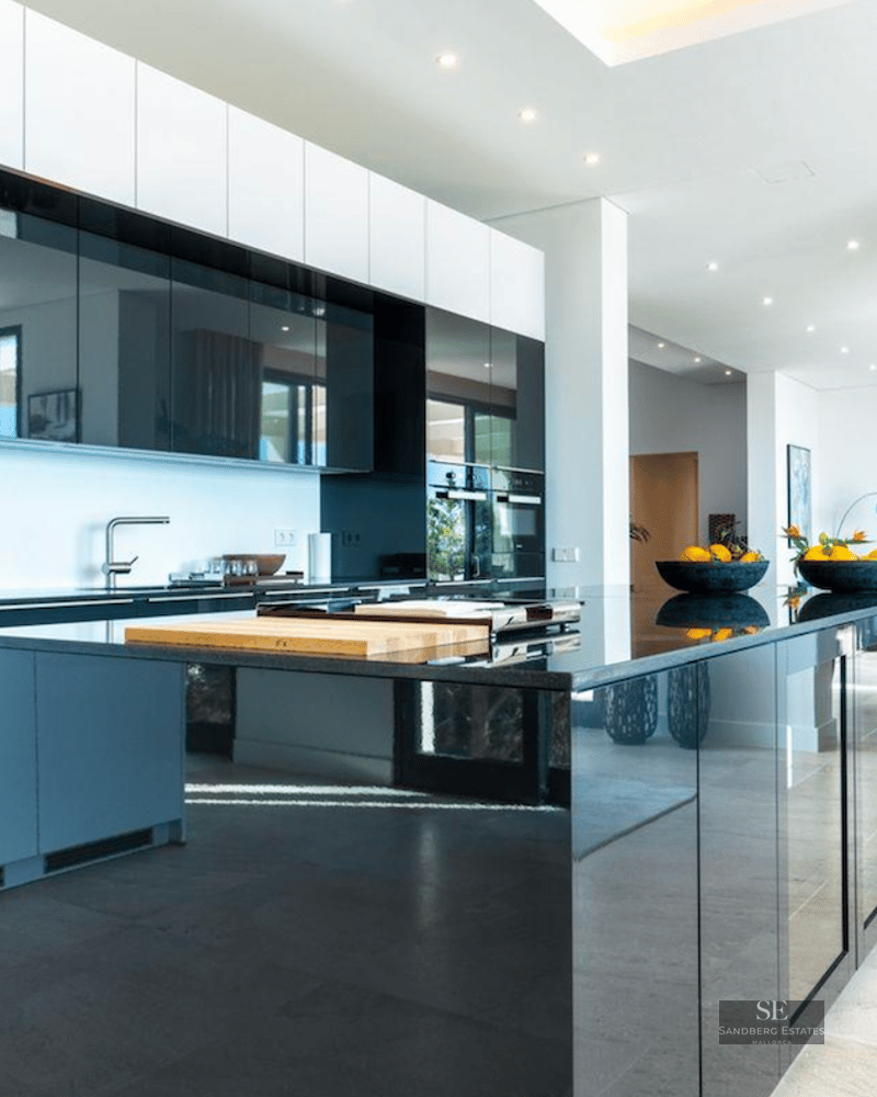 Luxury open-plan kitchen featuring high-gloss black cabinetry, a large central island, and contemporary design.