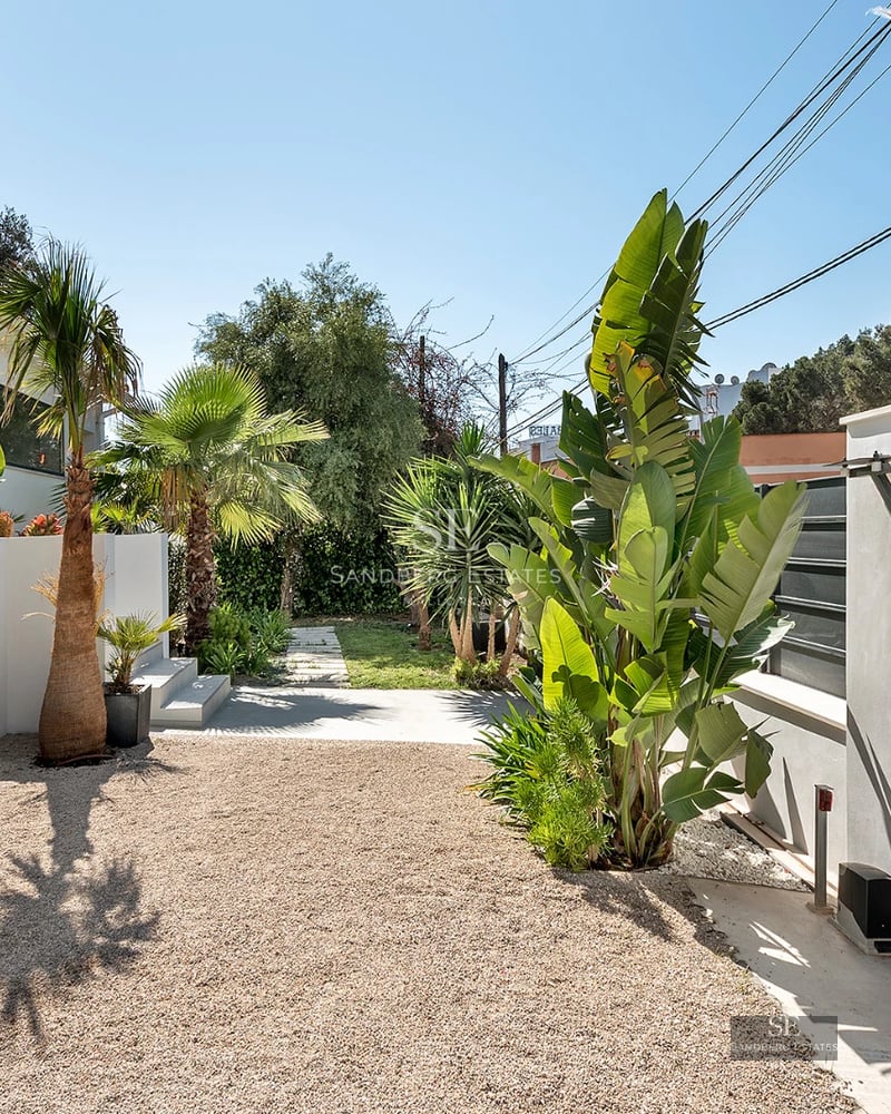 Exterior view of a modern villa with pool, large windows, gardens, and minimalist architecture.