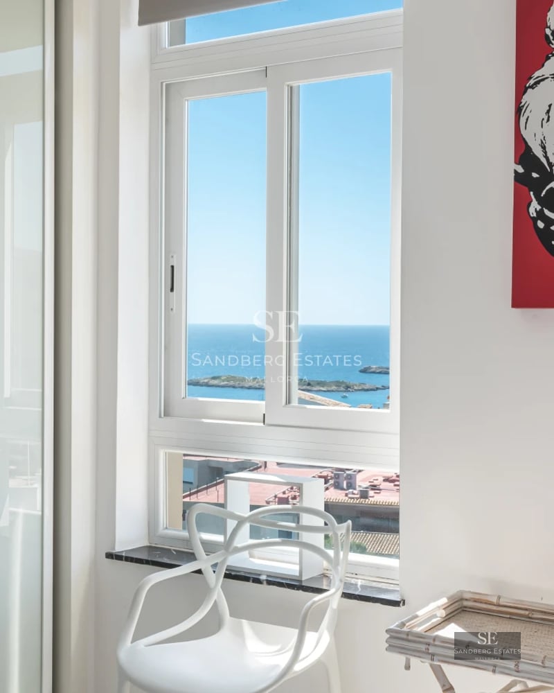 Panoramic view of a luxurious infinity pool surrounded by lush greenery and a modern house with large windows.