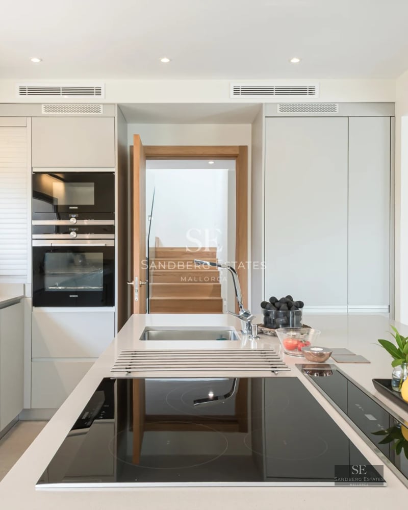 Spacious living room featuring panoramic windows offering a sea view. Modern sofa, textured rug, and ambient lighting.