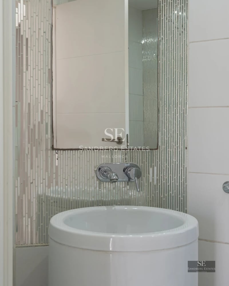 View of infinity pool with sun loungers, manicured garden, and modern architecture. Luxury and comfort in a tranquil setting.