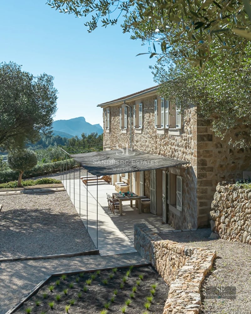 Panoramic view of a luxurious villa with infinity pool, sun loungers, and gardens. Modern architectural design with large windows.