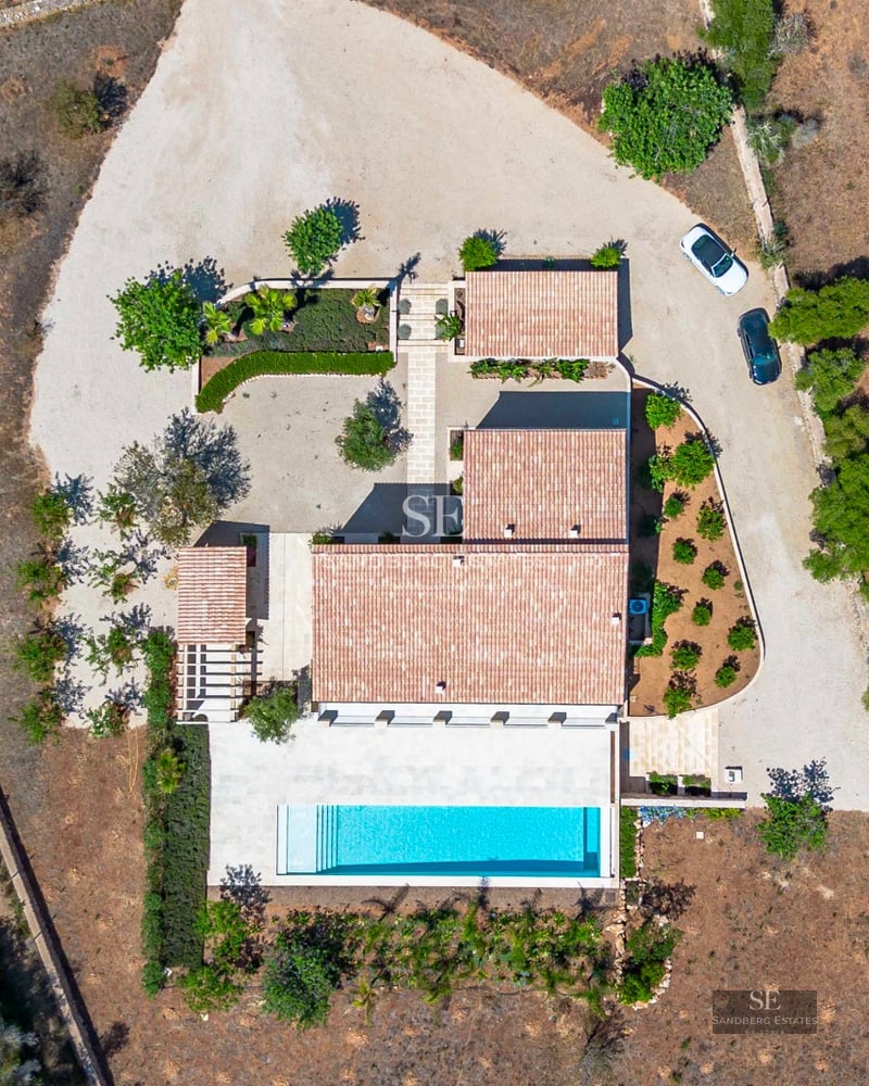 View of a modern villa featuring a swimming pool, garden, and terrace. Minimalist architecture, large windows, and natural light.