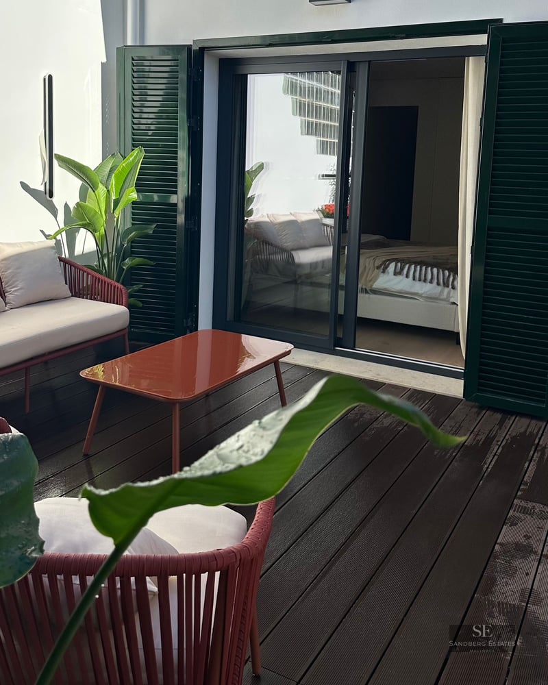 Private outdoor terrace with terracotta furniture, wooden decking, and green shutters next to a bedroom entrance.