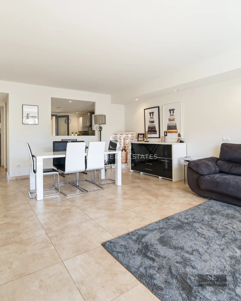 View of a reflecting pool surrounded by lawn and a modern house with large windows and a glass balcony.