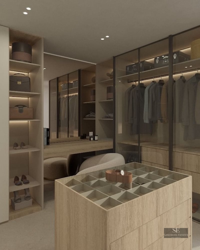 Modern walk-in closet with light wood cabinetry, glass wardrobes, a center jewelry island, and a vanity area.