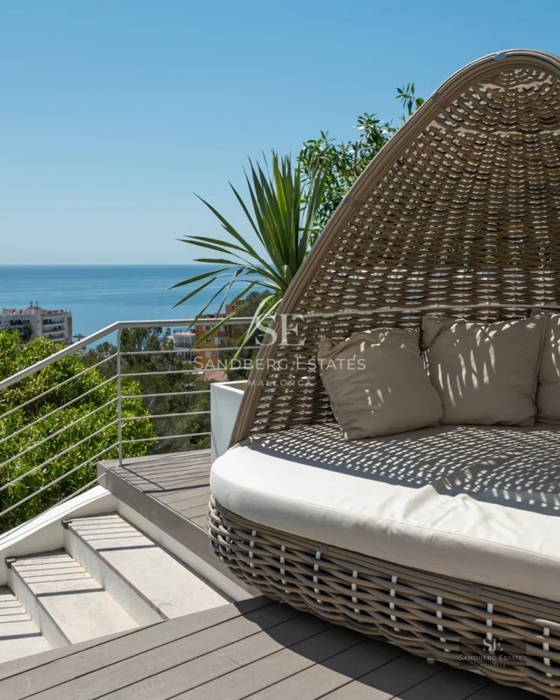 Pool view with loungers and umbrellas, surrounded by lush greenery and a modern house.