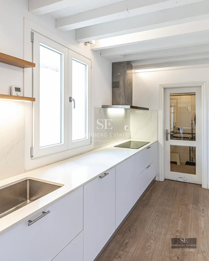 Spacious living room with floor-to-ceiling windows, modern sofas and access to a terrace with a view. Light wooden floors, abundant natural light.