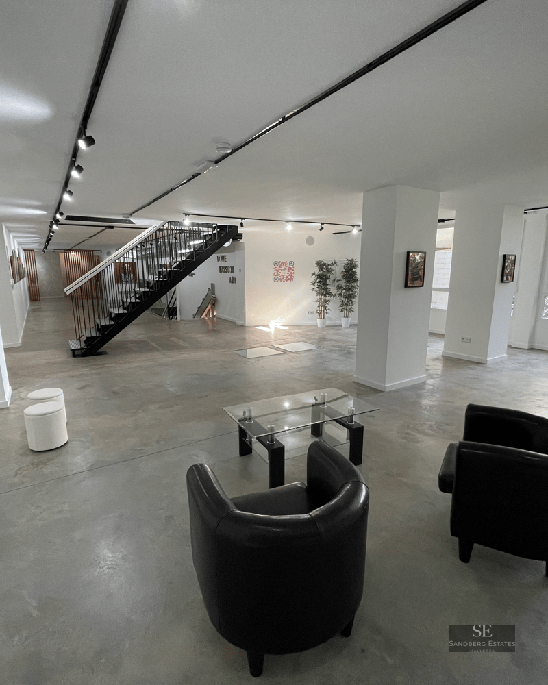 Spacious area with polished concrete floors, black leather armchairs, and a minimalist metal staircase.