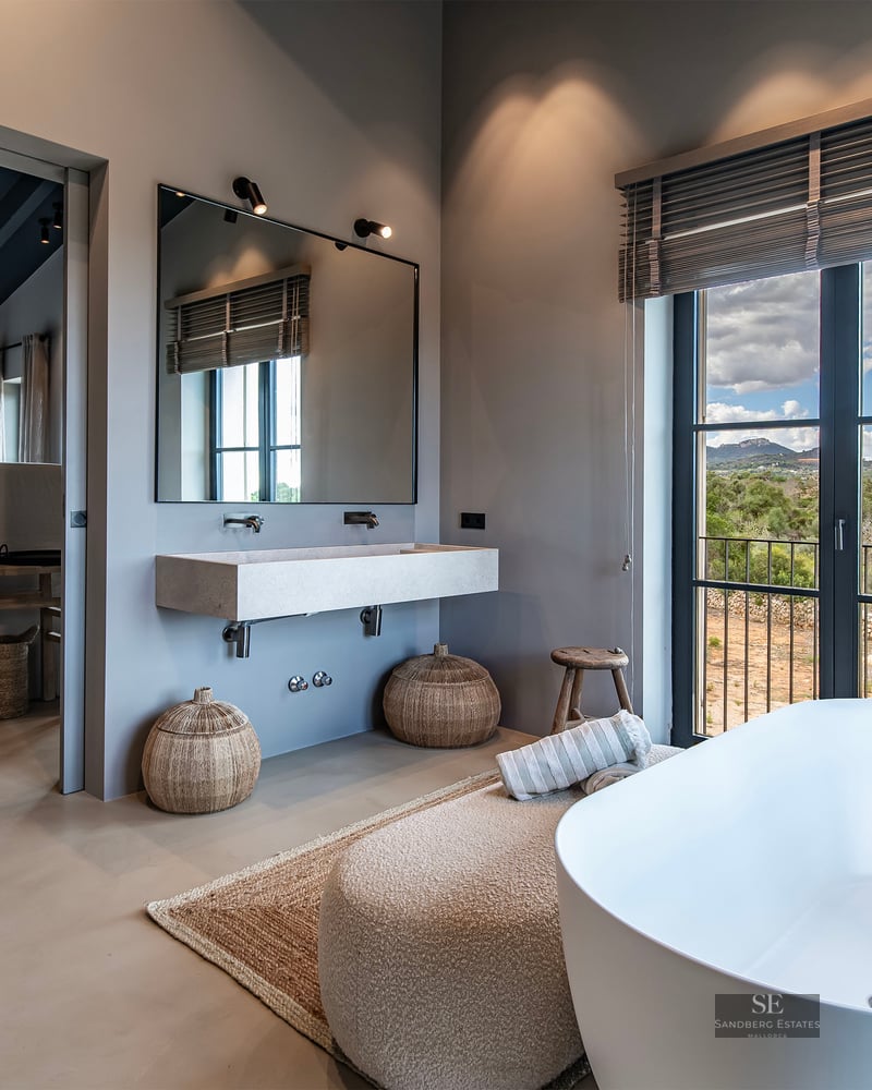 Modern master bathroom featuring a freestanding tub, floating sink, and large window overlooking a mountain landscape.