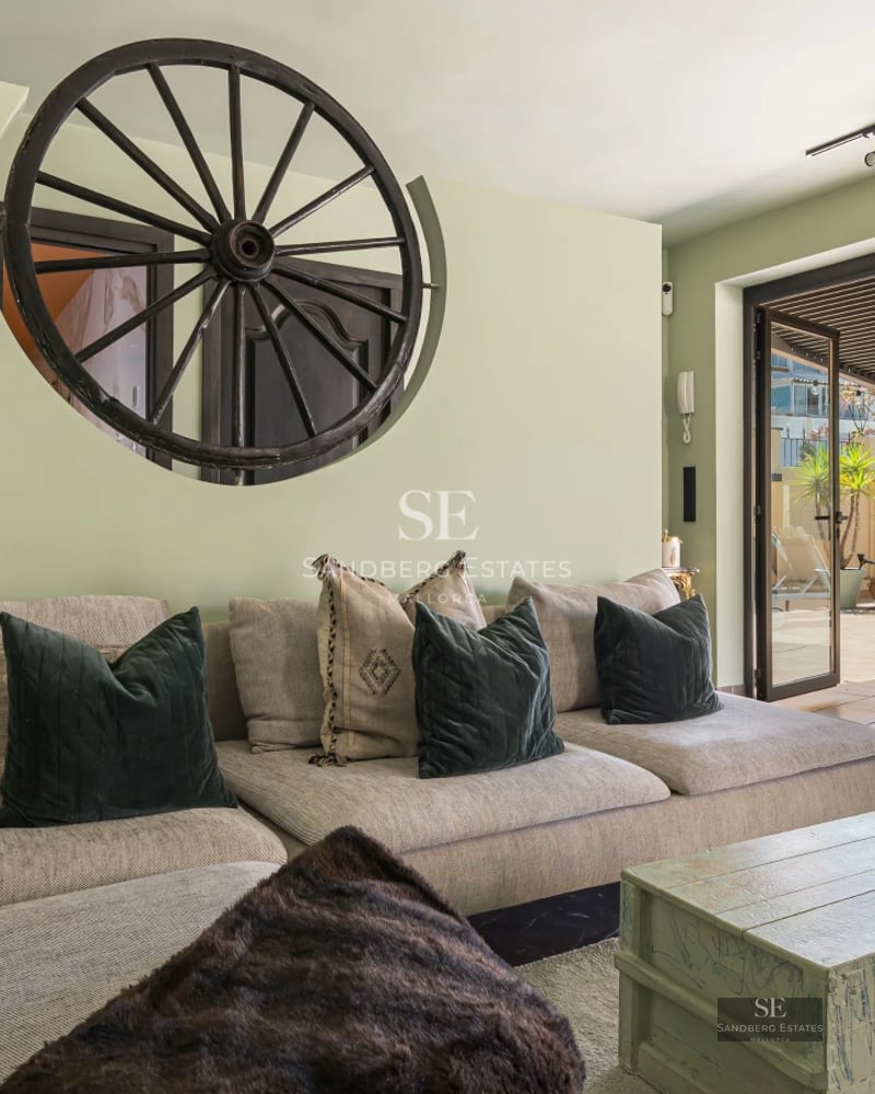 Spacious living room with floor-to-ceiling windows, light wood floors, modern furniture, and access to a terrace overlooking the pool and garden.