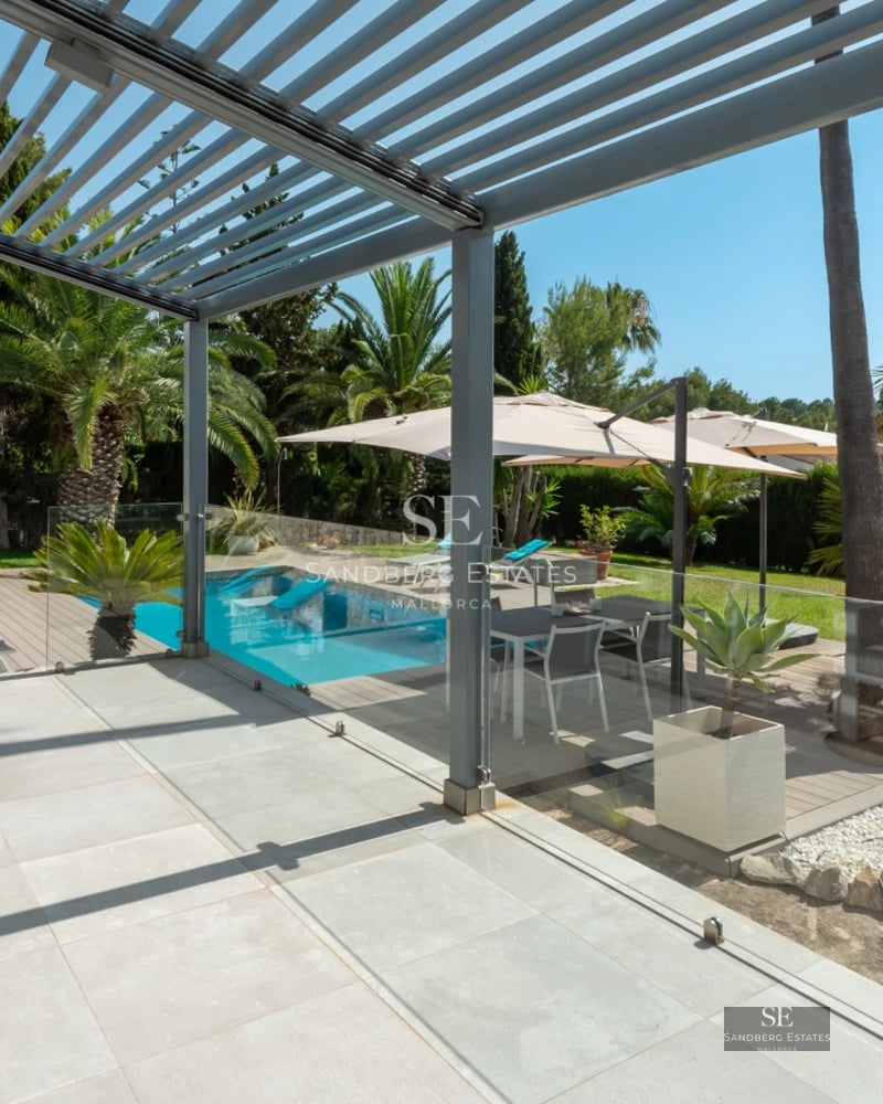 Spacious living room with modern fireplace, large windows, light wood floors, and minimalist decor. Abundance of natural light.