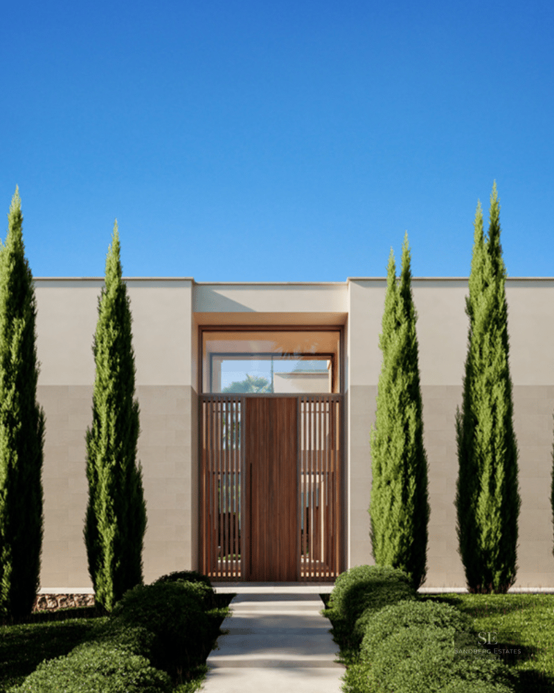 Symmetrical modern villa entrance featuring tall cypress trees, a wooden door, and a clear blue sky.