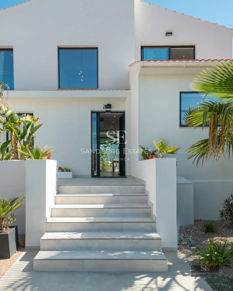 Exterior of modern villa with infinity pool, lounge chairs, garden, and panoramic views. Minimalist architecture with large windows.