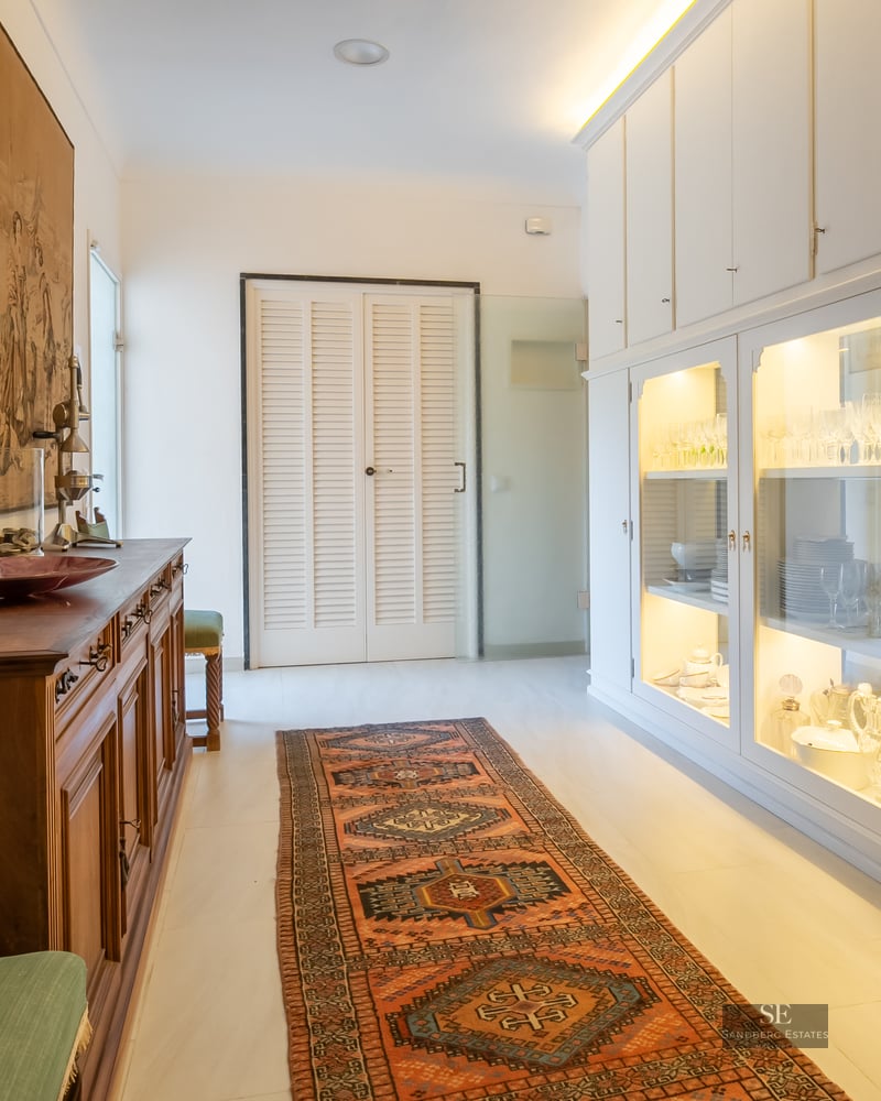 Hallway featuring a large historical tapestry, an oriental runner rug, and illuminated white glass display cabinets.