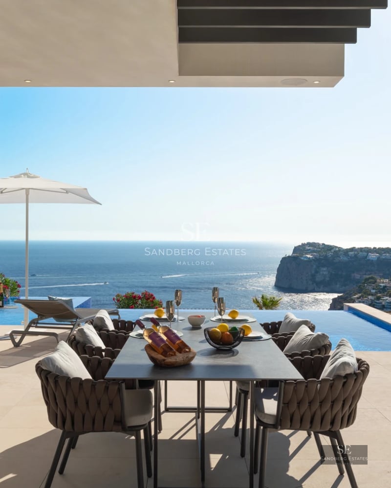 Spacious living room with large windows, light wood flooring, and minimalist decor. Ocean view from the white modular sofa.