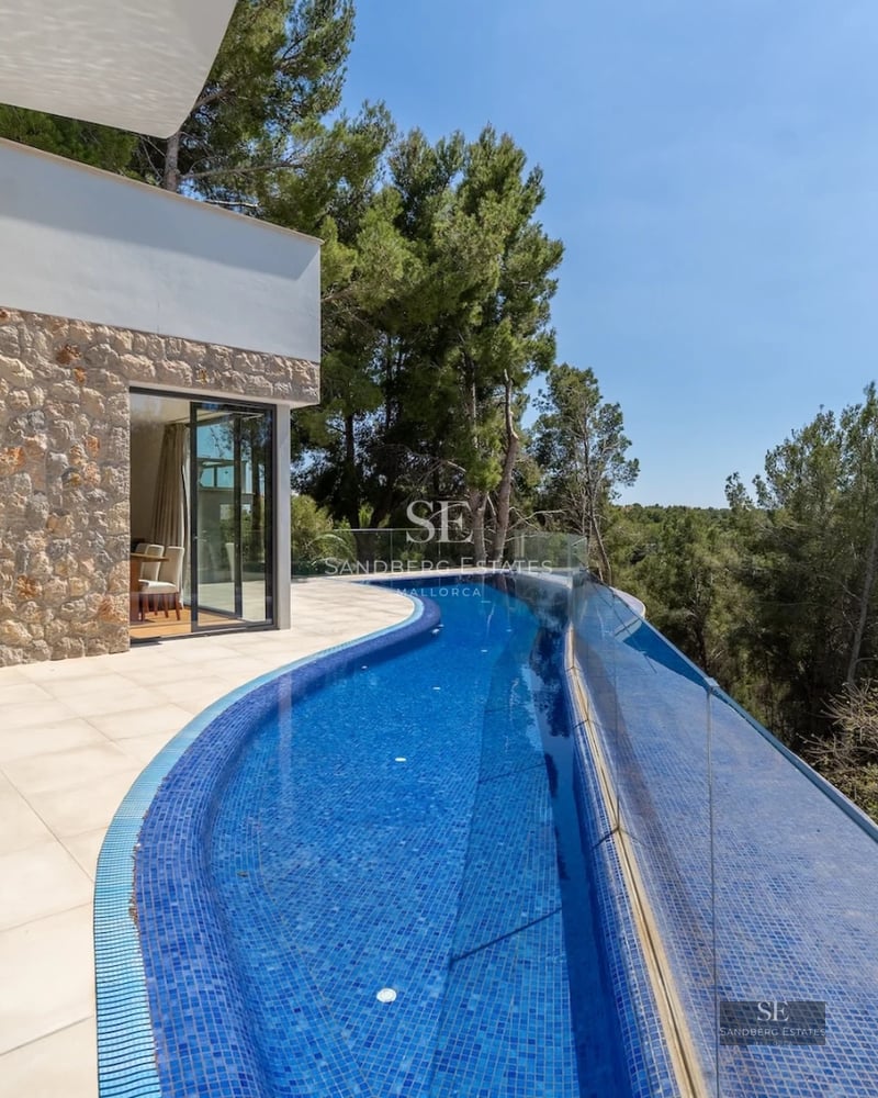 View of an elegant pool surrounded by manicured lawn and a modern house with large windows. Minimalist design and natural light.