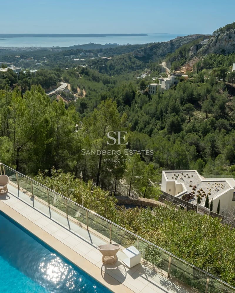 Expansive balcony with panoramic sea views. Modern furniture, glass railing, and retractable awning. Minimalist and elegant design.