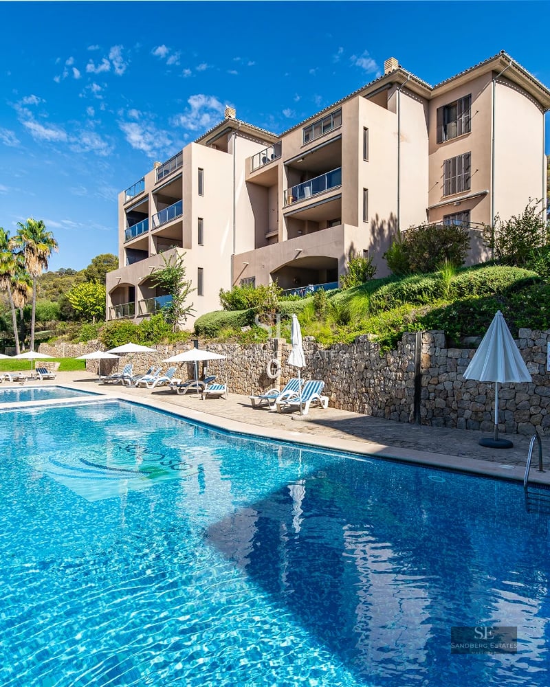 Aerial view of luxurious house with turquoise pool, garden, and terrace. Modern architecture with large windows.