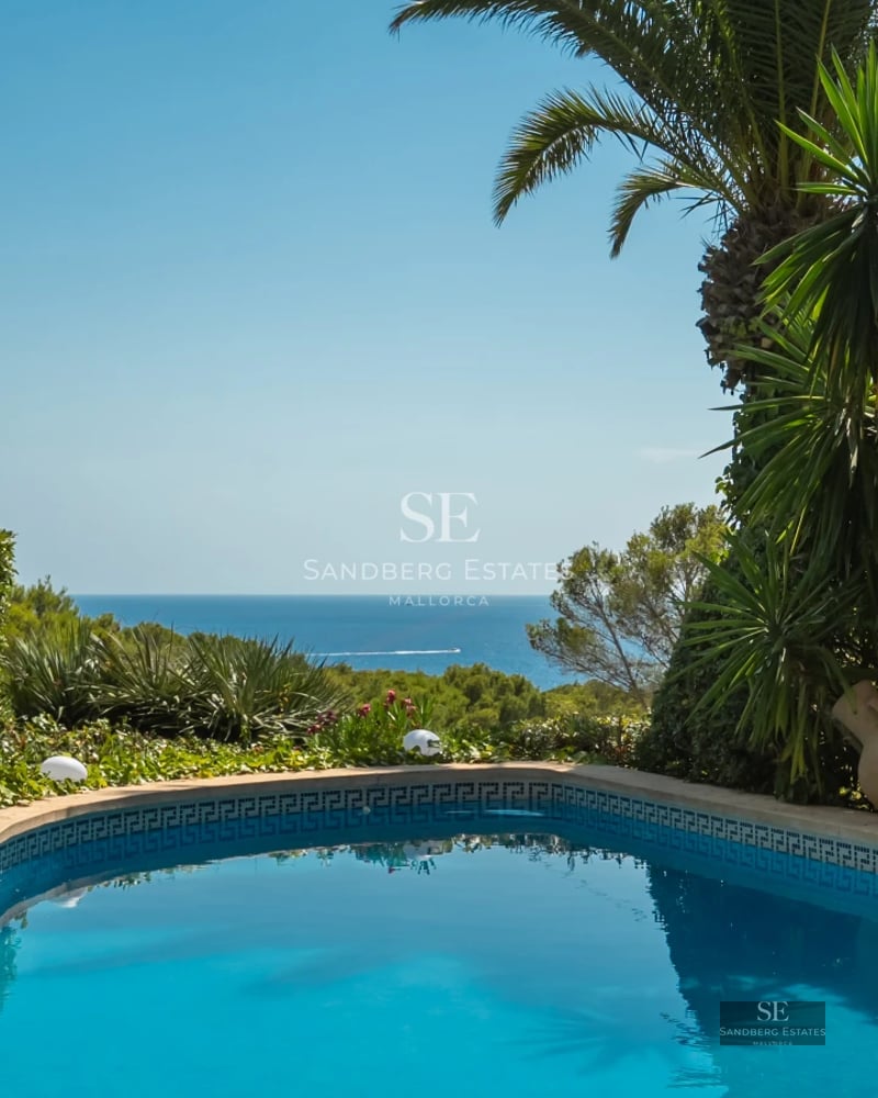 Balcony with glass railing and panoramic sea view. Modern furniture, soft lighting, and elegant design.