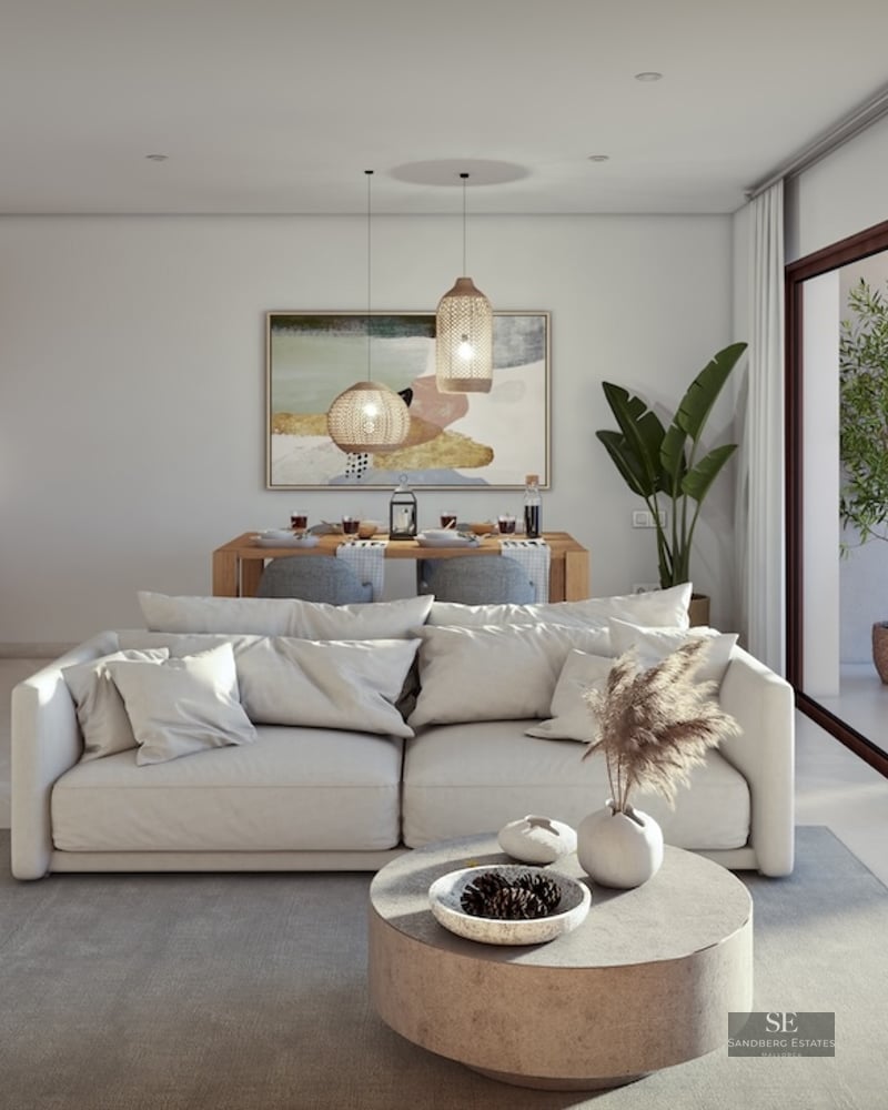 Modern living room with white sofa, stone coffee table, and large glass doors opening to a sunny terrace.