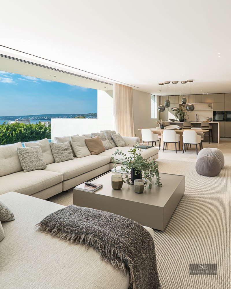 Spacious modern living room with large sectional sofa, floor-to-ceiling glass walls, and panoramic ocean views.