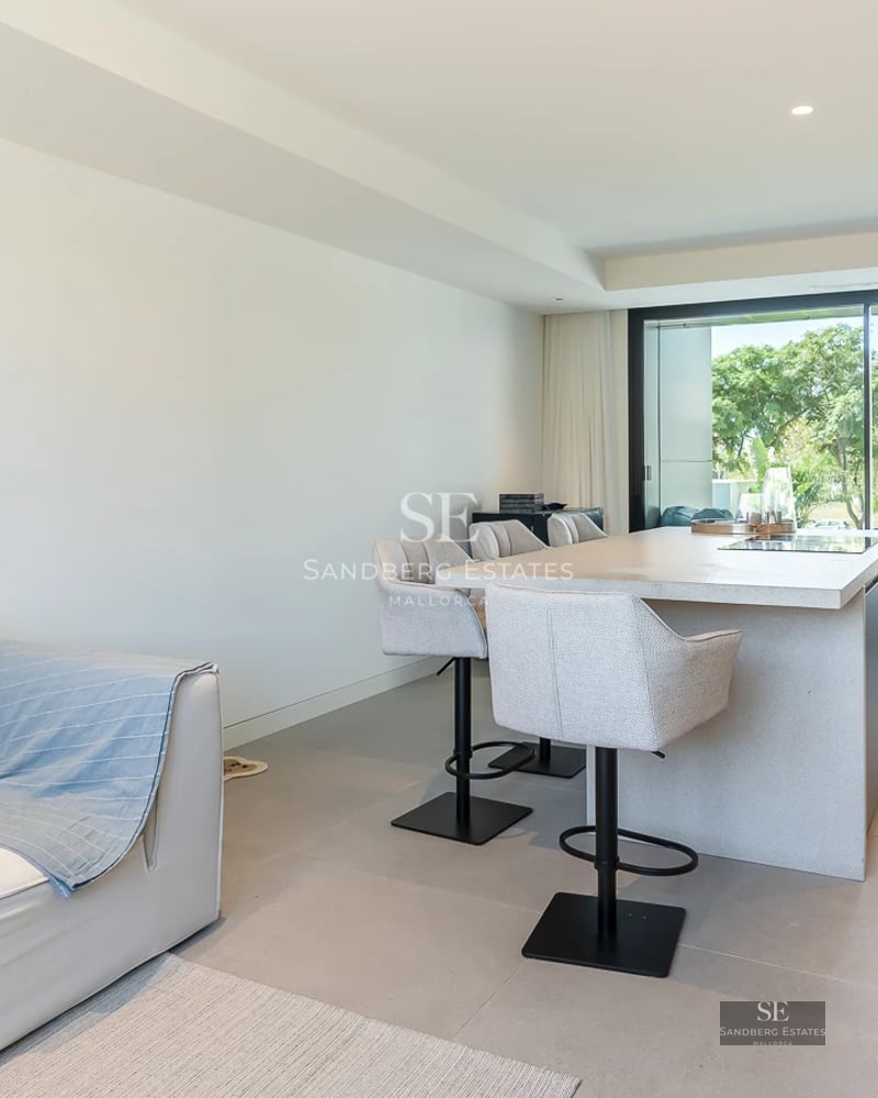 View of pool and modern house with large windows, lush greenery, and partially cloudy sky. Contemporary architecture.