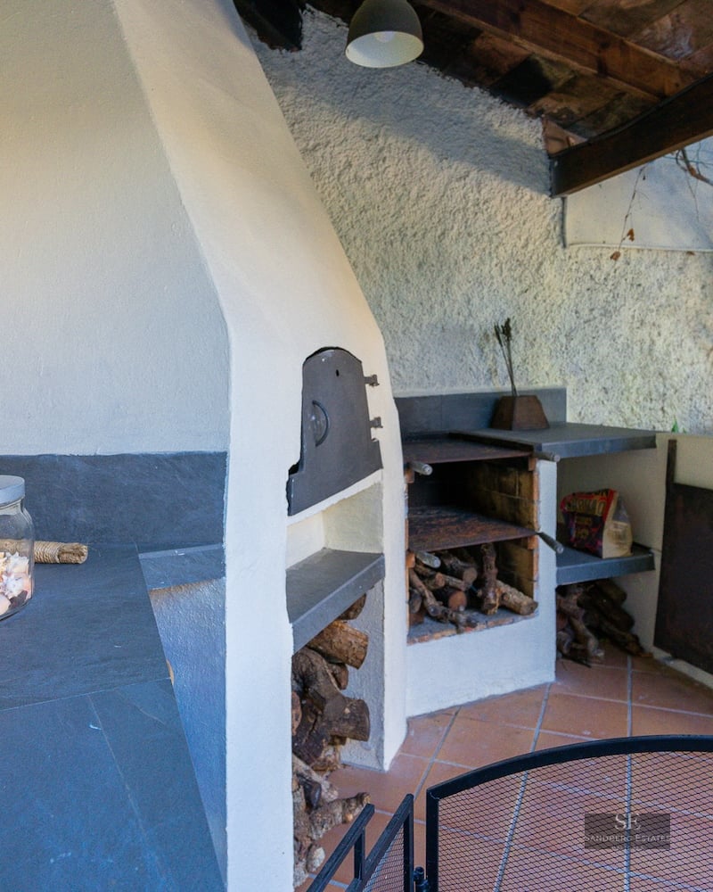 Covered outdoor terrace with built-in wood-fired oven, slate countertops, and terracotta tile floor.