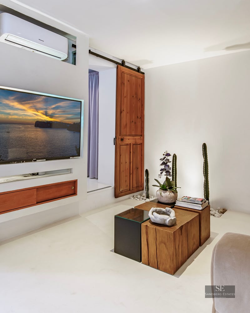 Cozy white living room featuring a wall-mounted TV, a large beige sofa, and a rustic wooden sliding barn door.