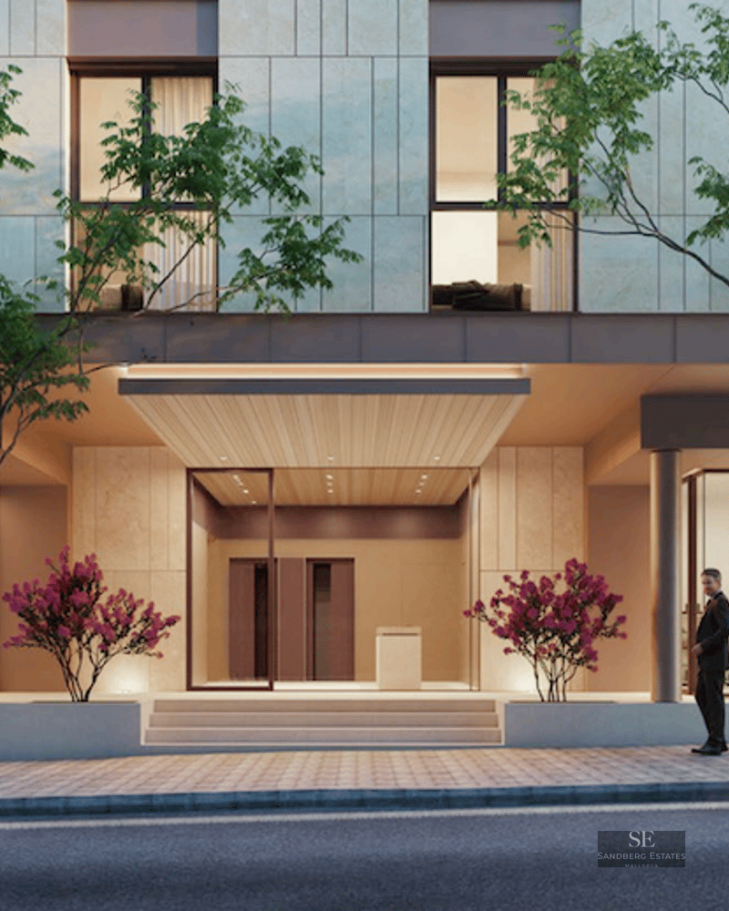 Ground floor of a modern building with central entrance, glass storefronts, sidewalk trees, and luxury cars.