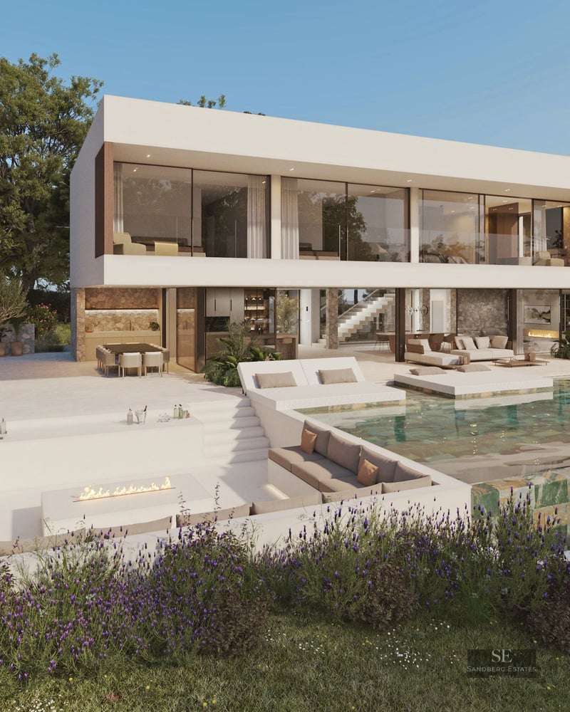 Modern white villa featuring a green stone infinity pool, sunken fire pit seating, and lush landscaping.