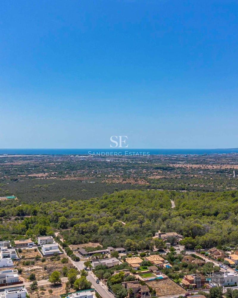 Spacious living room with large windows, sea view, light wood floors, and modern furniture in neutral tones.